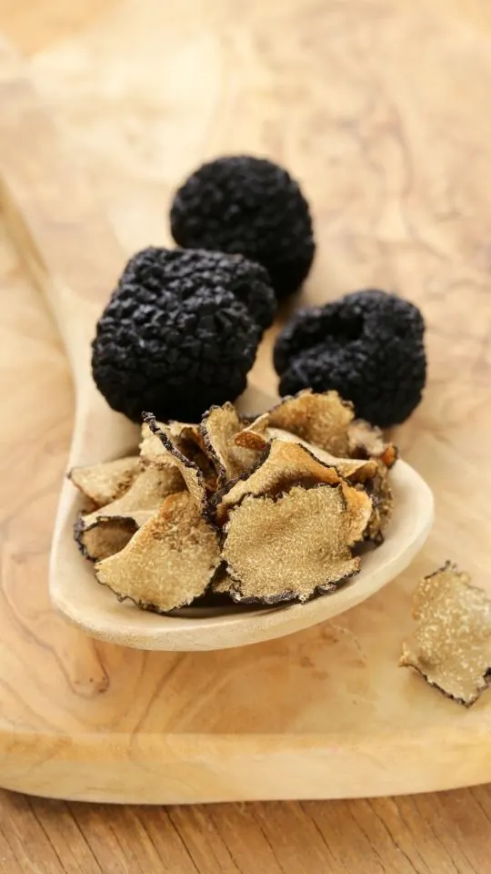 Tartufi neri dell'Appennino Bolognese affettati su un cucchiaio di legno
